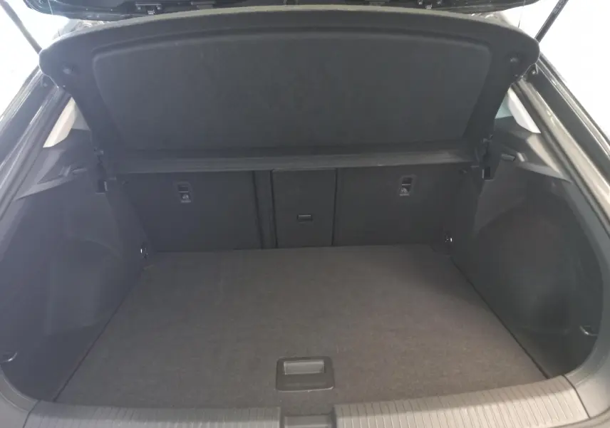 Coffre ouvert vu de l'arrière d'un Volkswagen T-Roc 1.5 TSI 150 DSG7 VW Edition gris Indium, intérieur noir.