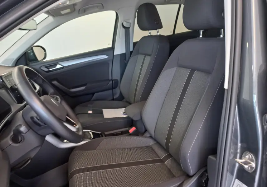 Vue intérieure côté gauche du Volkswagen T-Roc 1.5 TSI 150 DSG7 VW Edition 2025 en gris Indium, sièges tissu noir et gris.