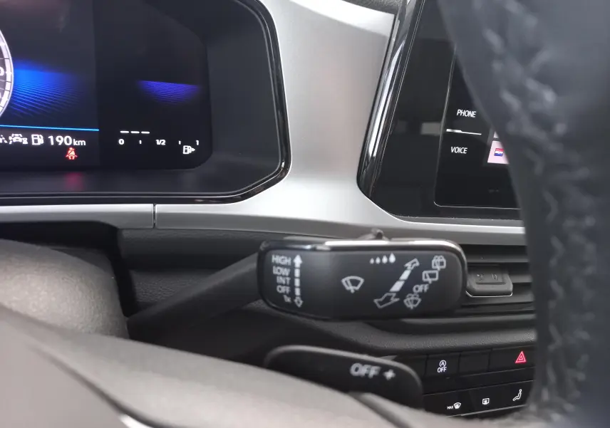 Vue intérieure rapprochée du tableau de bord du Volkswagen T-Roc gris Indium, avec commandes d’essuie-glace et affichage numérique.