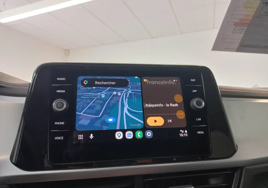 Écran tactile central du Volkswagen T-Roc 2025 affichant navigation et radio, avec commandes autour en noir brillant.