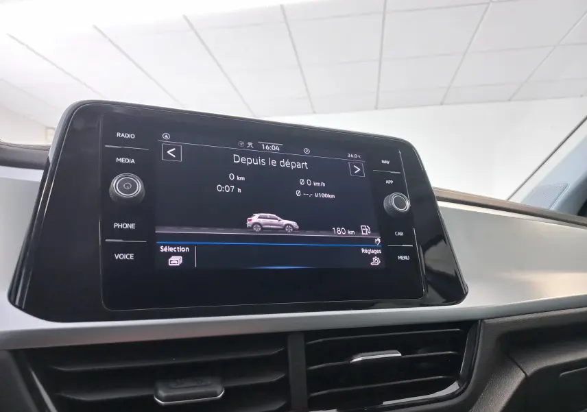 Écran central tactile du Volkswagen T-Roc 2025 affichant les données de trajet, dans un intérieur clair.