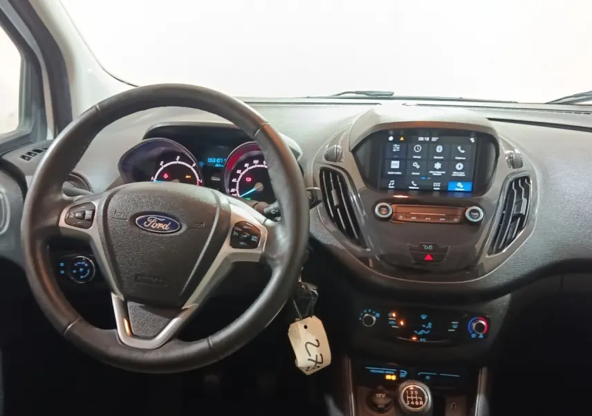 Vue intérieure centrée sur le volant cuir multifonctions et le tableau de bord numérique du Ford Grand Tourneo Connect blanc.