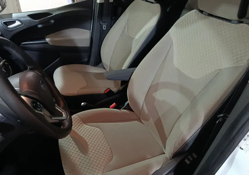 Vue intérieure côté conducteur du Ford Grand Tourneo Connect blanc, sièges avant beige avec texture matelassée.