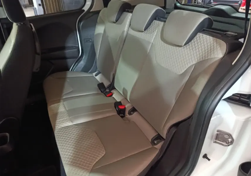 Vue intérieure côté droit sur la banquette arrière beige du Ford Grand Tourneo Connect blanc, avec porte ouverte.
