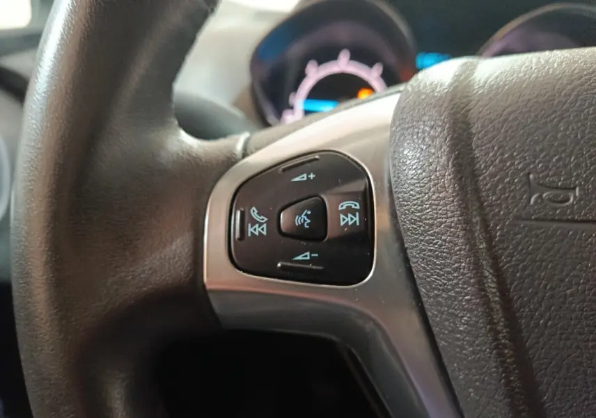 Gros plan sur les commandes vocales et téléphone du volant en cuir noir du Ford Grand Tourneo Connect blanc 2020.