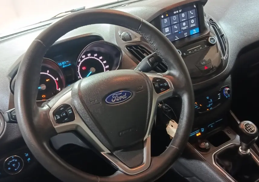 Vue intérieure centrée sur le volant cuir multifonctions et tableau de bord digital du Ford Grand Tourneo Connect blanc.
