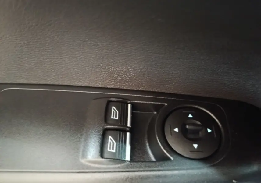 Gros plan sur les commandes de lève-vitres et réglage des rétroviseurs côté conducteur du Ford Grand Tourneo Connect blanc.