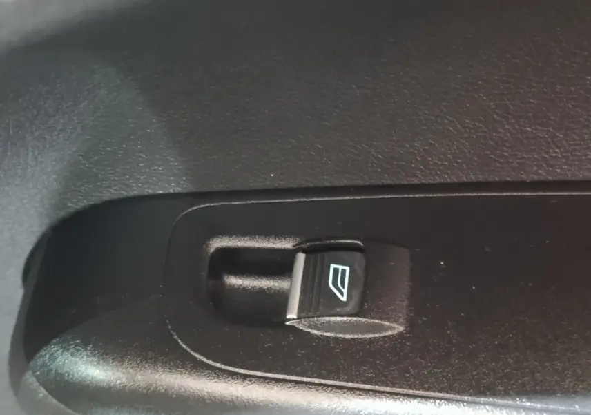 Bouton de commande électrique de lève-vitre noir sur panneau intérieur de porte d’un Ford Grand Tourneo Connect blanc.