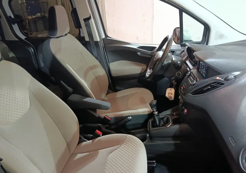 Vue intérieure côté conducteur du Ford Grand Tourneo Connect 2020, sièges beige et volant cuir avec boîte manuelle.