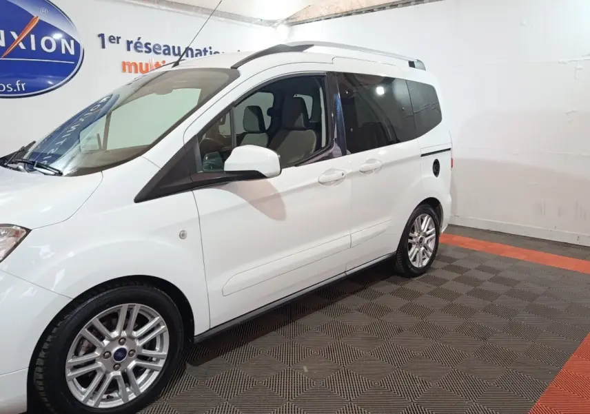 Vue côté gauche en 3/4 arrière d’un Ford Grand Tourneo Connect blanc, avec jantes alliage et vitres teintées.