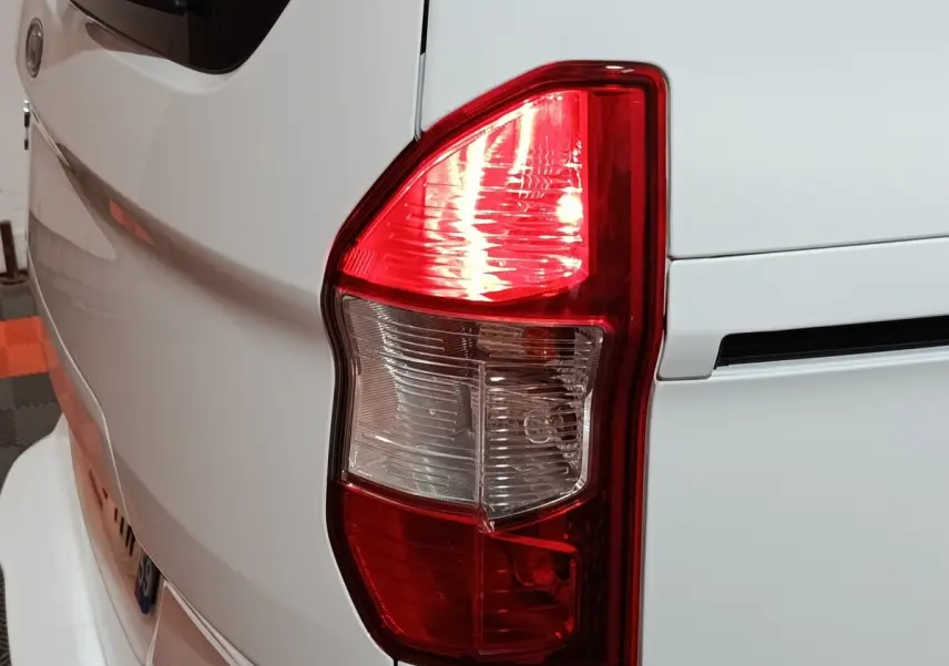 Gros plan sur le feu arrière droit d’un Ford Grand Tourneo Connect blanc, montrant les détails du feu stop et clignotant.