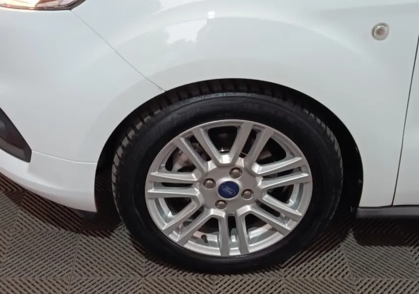 Gros plan sur la roue avant gauche argentée d’un Ford Grand Tourneo Connect blanc, avec partie de l’aile visible.