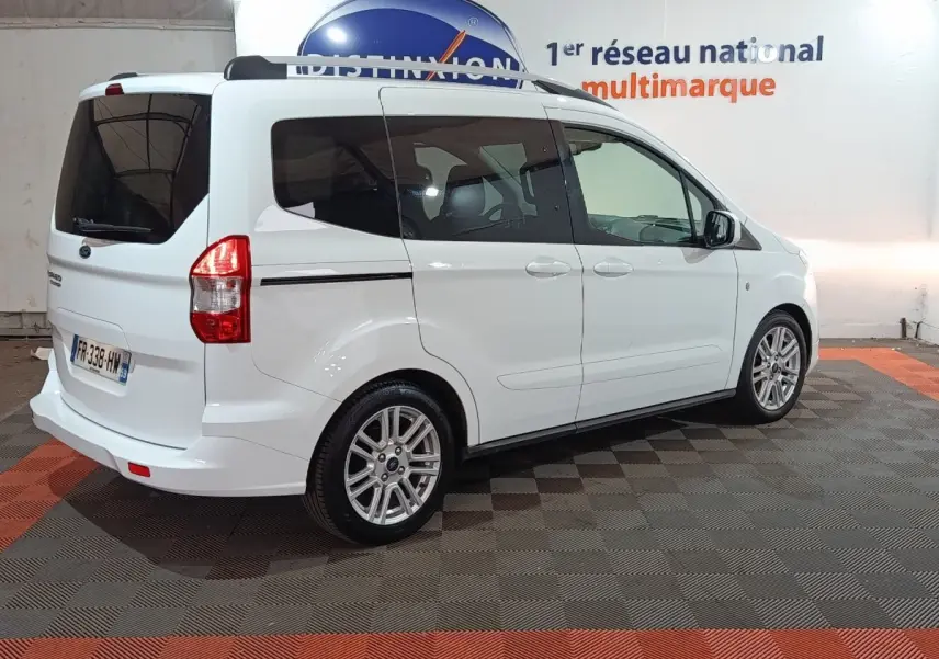 Ford Grand Tourneo Connect blanc vu en 3/4 arrière droit dans un showroom avec jantes alliage et vitres teintées.