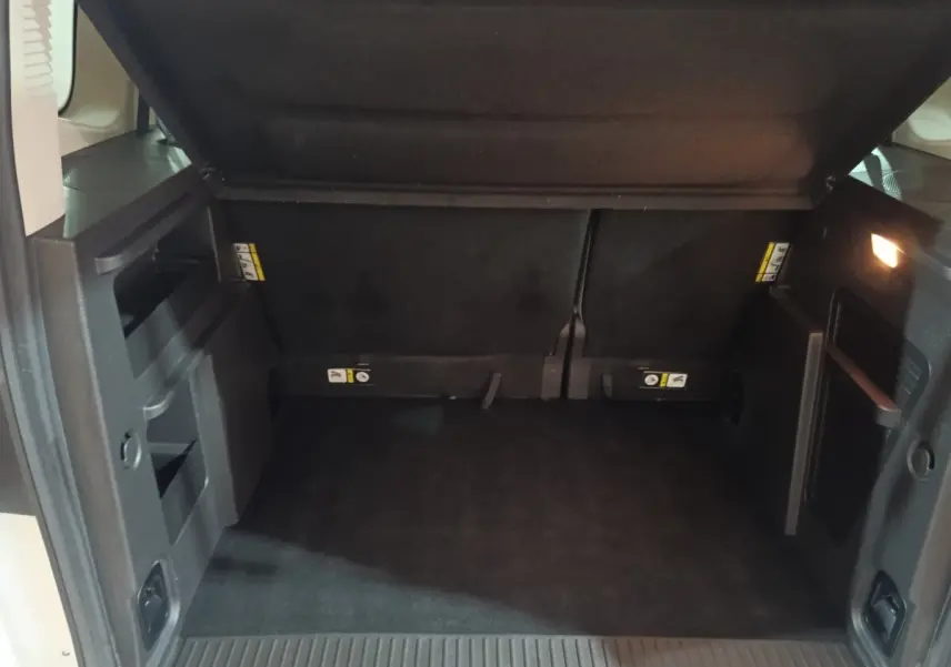 Coffre ouvert du Ford Grand Tourneo Connect blanc, vue intérieure arrière montrant l'espace de chargement noir.