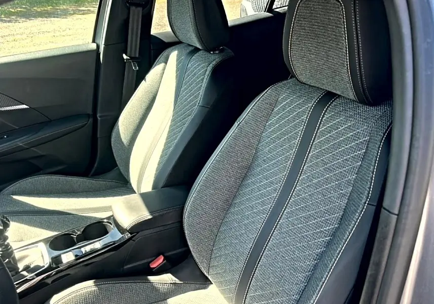 Vue intérieure rapprochée des sièges avant en tissu gris embossé du Peugeot 2008 1.2 100 Allure 2025.