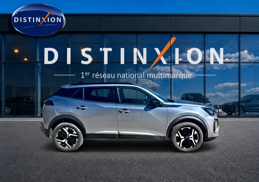 Peugeot 2008 1.2 100 Allure gris Artense vue de profil côté gauche devant une vitrine avec logo Distinxion.