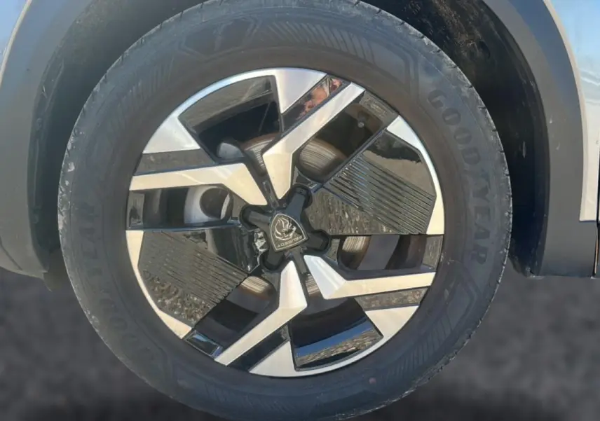 Gros plan sur la jante alu bicolore du côté avant droit d’un Peugeot 2008 gris Artense, pneu Goodyear visible.