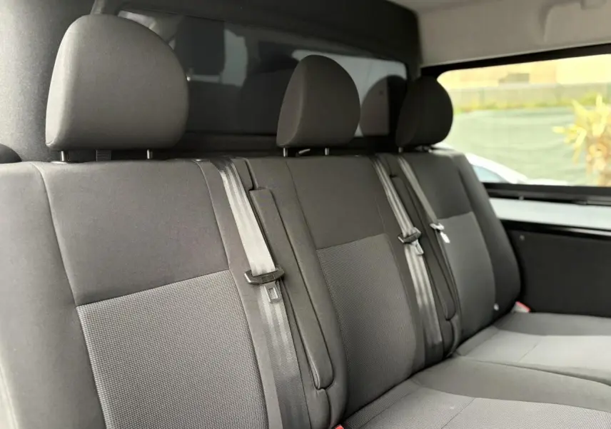 Vue intérieure du siège arrière trois places du Citroën Jumpy noir Perla avec appuie-têtes et ceintures visibles.