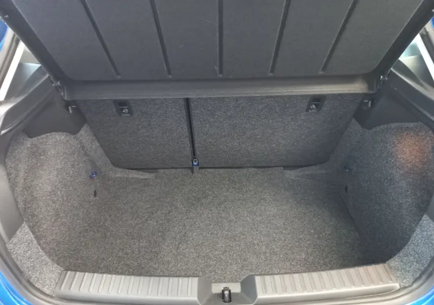 Coffre ouvert vu de l'arrière d'une SEAT Ibiza 2025 bleu saphir, montrant un espace de chargement vide et tapissé.
