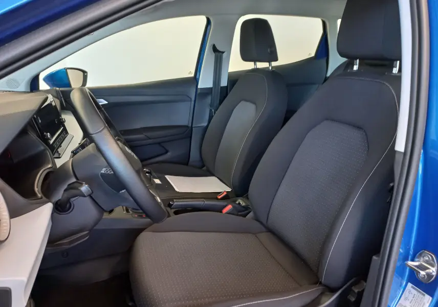 Vue intérieure côté conducteur de la SEAT IBIZA 2025 bleu saphir, montrant les sièges noirs et le volant.