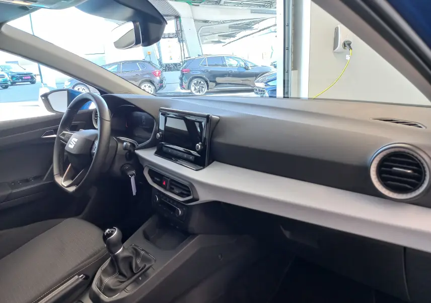 Intérieur de la SEAT Ibiza 1.0 TSI 95 Copa 2025 en bleu saphir, vue côté conducteur sur tableau de bord et levier de vitesses manuel.