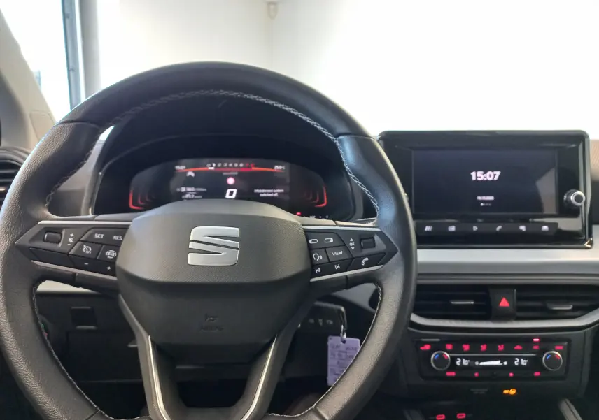 Vue intérieure centrée sur le volant noir de la SEAT Ibiza 2025, avec tableau de bord digital et écran tactile allumé.