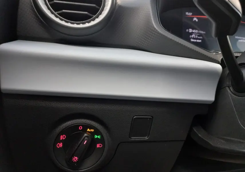 Détail intérieur du tableau de bord côté gauche de la SEAT Ibiza bleu saphir, avec commande des phares et aérateur rond.