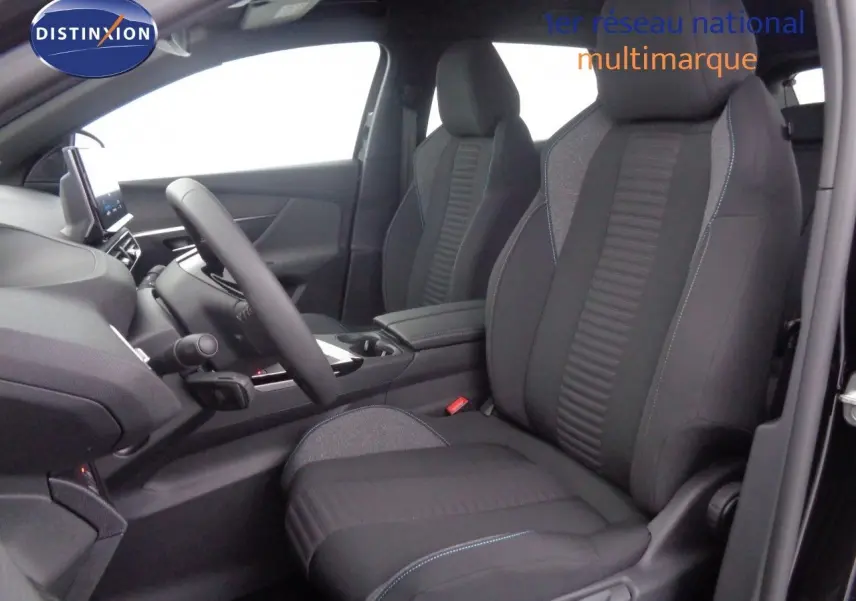 Vue intérieure côté conducteur du Peugeot 3008 2023 avec sièges tissu gris noir et surpiqûres bleues, volant et console centrale visibles.