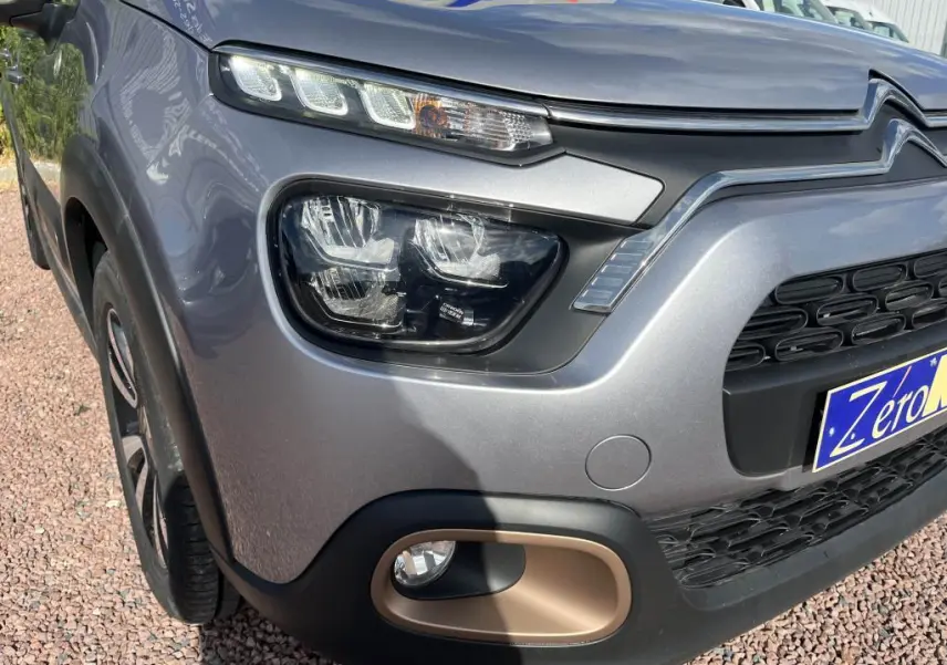 Gros plan sur l'avant droit gris métallisé d'une Citroën C3 2022, mettant en valeur ses phares LED et antibrouillard.