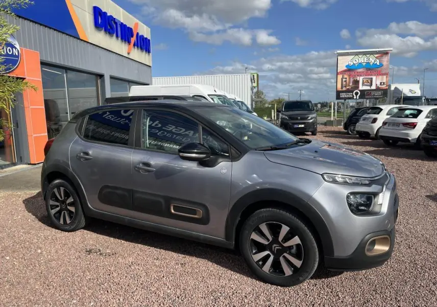 Vue de profil côté gauche d'une Citroën C3 gris métallisé avec toit noir et protections latérales distinctives.