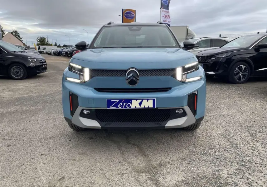 Vue avant d'une Citroën C3 Aircross hybride bleu Monte Carlo avec toit noir et feux LED allumés sur parking.