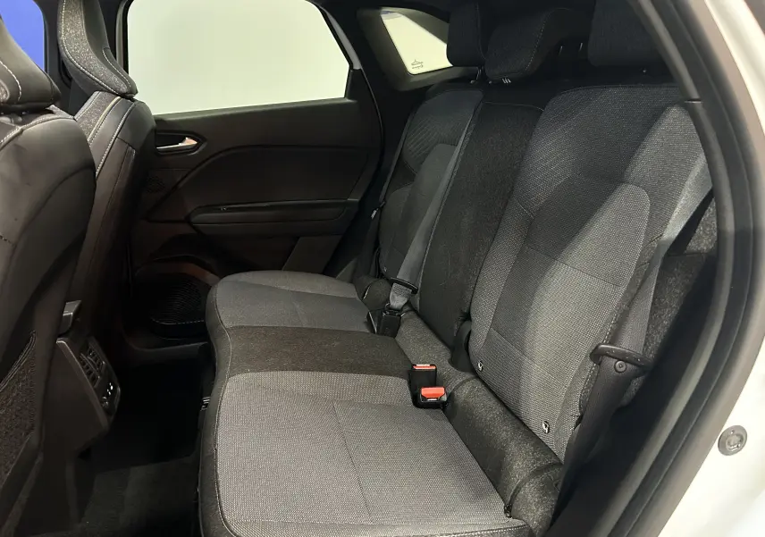 Vue côté droit de l'habitacle arrière du Renault Symbioz blanc nacré, avec sièges tissu gris et ceintures visibles.