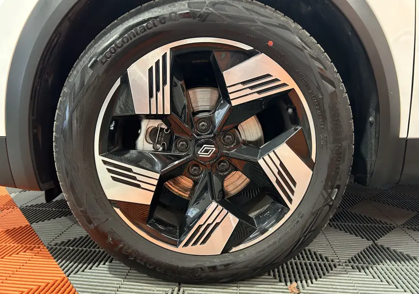 Gros plan sur la roue avant droite du Renault Symbioz blanc nacré avec jante noire et argentée au design géométrique.