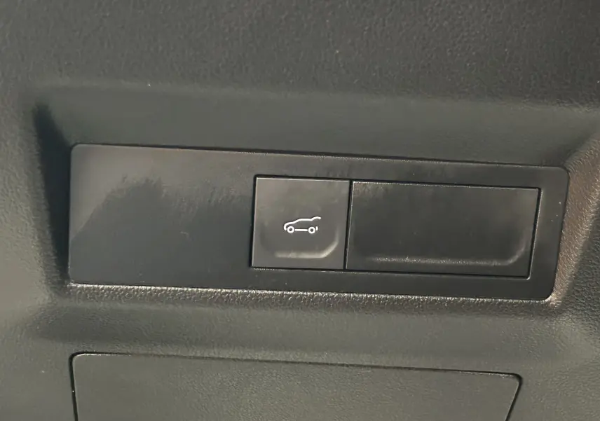 Bouton de hayon électrique noir avec pictogramme blanc dans l'habitacle d'une Renault Symbioz blanc nacré 2025 E-Tech Hybrid.