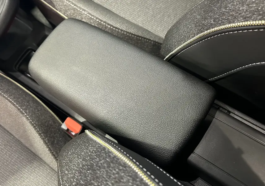 Gros plan sur l'accoudoir central en cuir noir avec surpiqûres blanches, entre les sièges tissu gris du Renault Symbioz 2025.