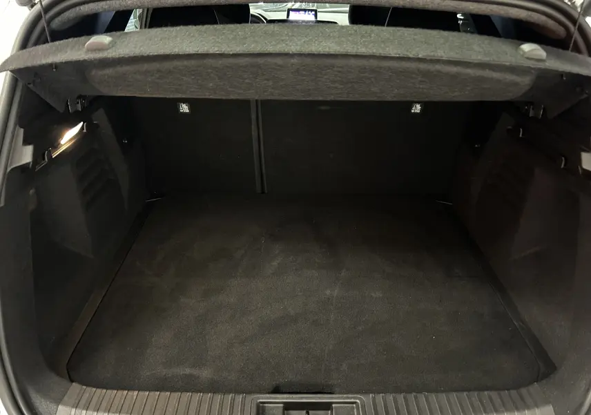 Coffre ouvert spacieux et propre du Renault Symbioz blanc nacré, vue intérieure arrière avec cache-bagages relevé.