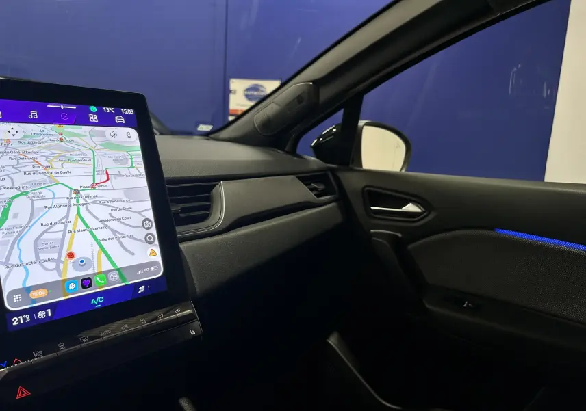 Vue intérieure côté passager du Renault Symbioz blanc nacré 2025, avec écran GPS tactile allumé et éclairage d'ambiance bleu.