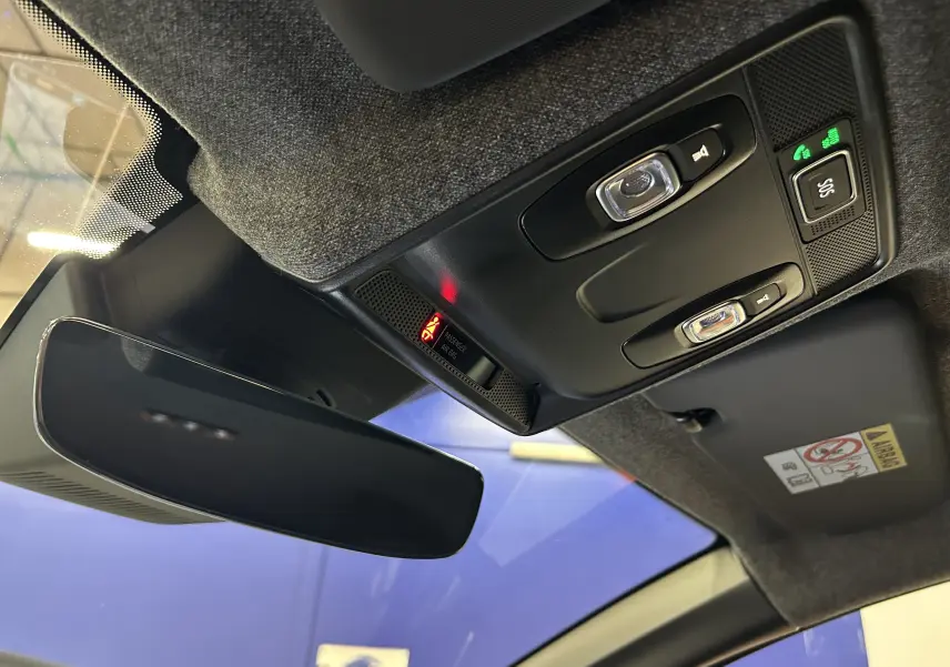 Vue intérieure en contre-plongée du rétroviseur central et du plafonnier avec commandes lumineuses dans une Renault Symbioz blanc nacré.