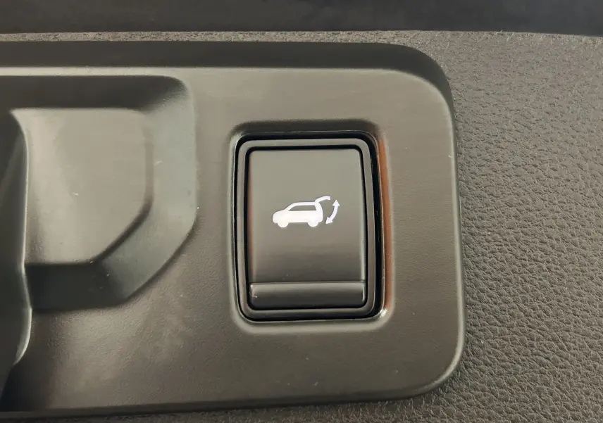 Bouton noir intérieur du hayon électrique avec pictogramme blanc d'ouverture sur Renault Symbioz E-Tech blanc nacré 2025.