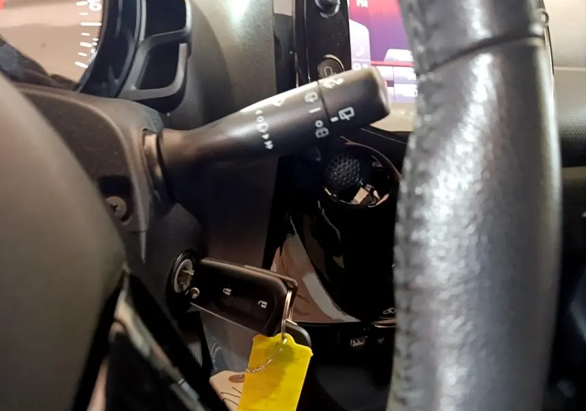 Gros plan intérieur côté gauche sur le volant cuir et la clé insérée dans le contact d'une Citroën C1 gris clair 2019.