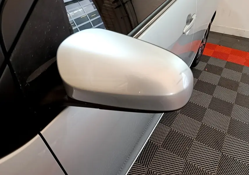 Gros plan sur le rétroviseur côté gauche d'une Citroën C1 gris clair, avec partie latérale visible en intérieur.