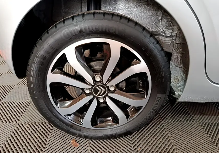 Gros plan sur la roue avant droite gris clair d'une Citroën C1 2019 avec jante alliage noire et argentée.