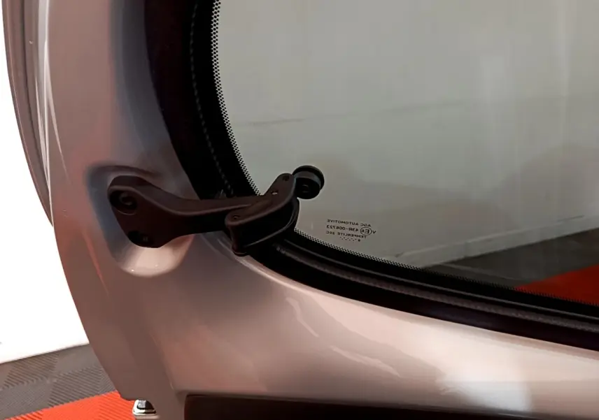 Gros plan sur la charnière de la porte arrière droite d'une Citroën C1 gris clair 2019, finition Shine.