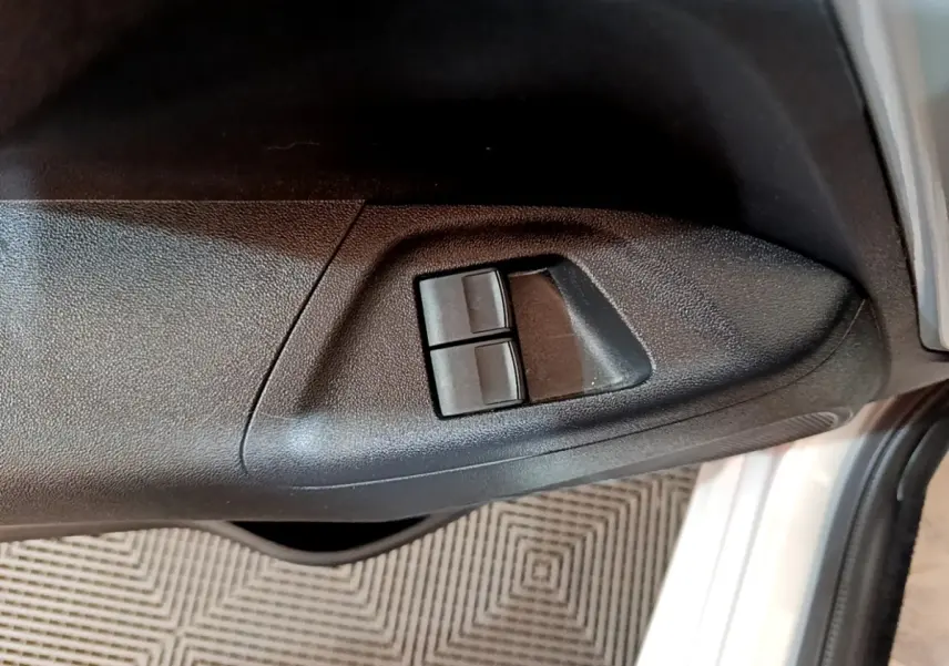 Gros plan sur les commandes de lève-vitres côté conducteur d’une Citroën C1 gris clair, porte ouverte.