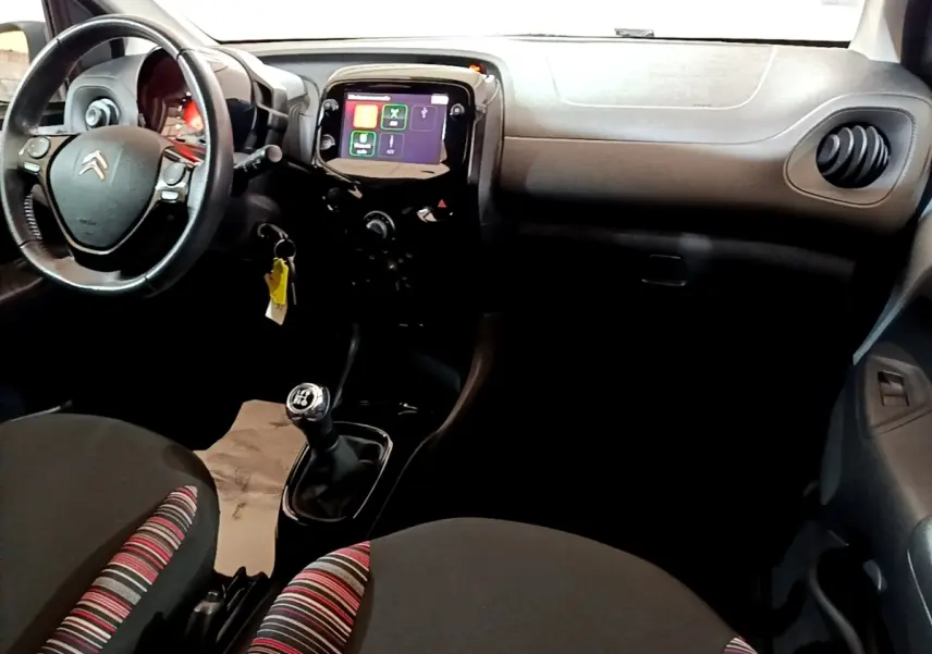 Intérieur de Citroën C1 2019 vu côté conducteur, tableau de bord noir avec écran tactile et volant cuir multifonctions.