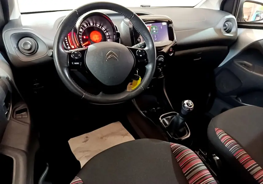 Intérieur de la Citroën C1 2019 vu de face, volant cuir, tableau de bord avec écran tactile 7 pouces et levier de vitesses manuel.