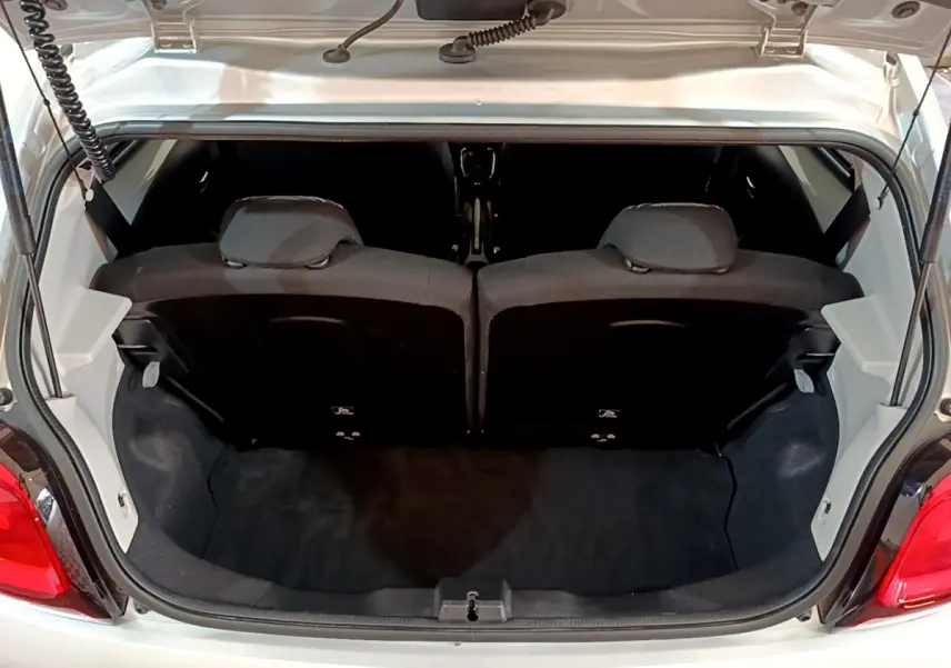 Coffre ouvert vu de l'arrière d'une Citroën C1 gris clair, montrant la banquette arrière et l'espace de chargement.