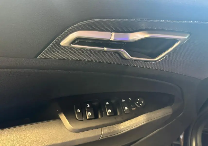 Gros plan sur la poignée intérieure et les commandes des vitres côté conducteur d’un KIA Sportage noir 2022.