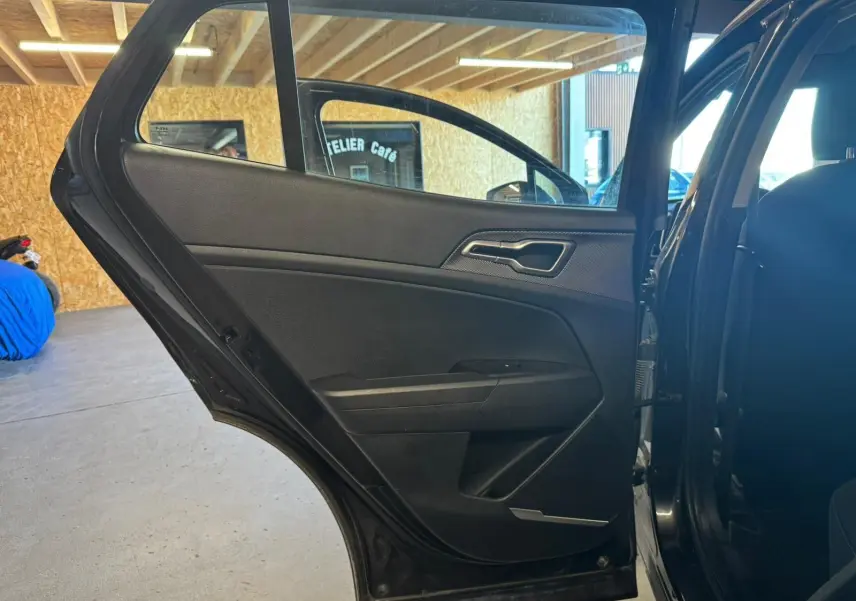 Vue intérieure de la porte arrière gauche noire du Kia Sportage 2022, mettant en valeur sa garniture sobre et moderne.