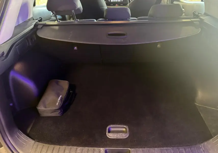 Vue intérieure du coffre noir du Kia Sportage 2022, avec cache-bagages et trousse de sécurité visible à gauche.